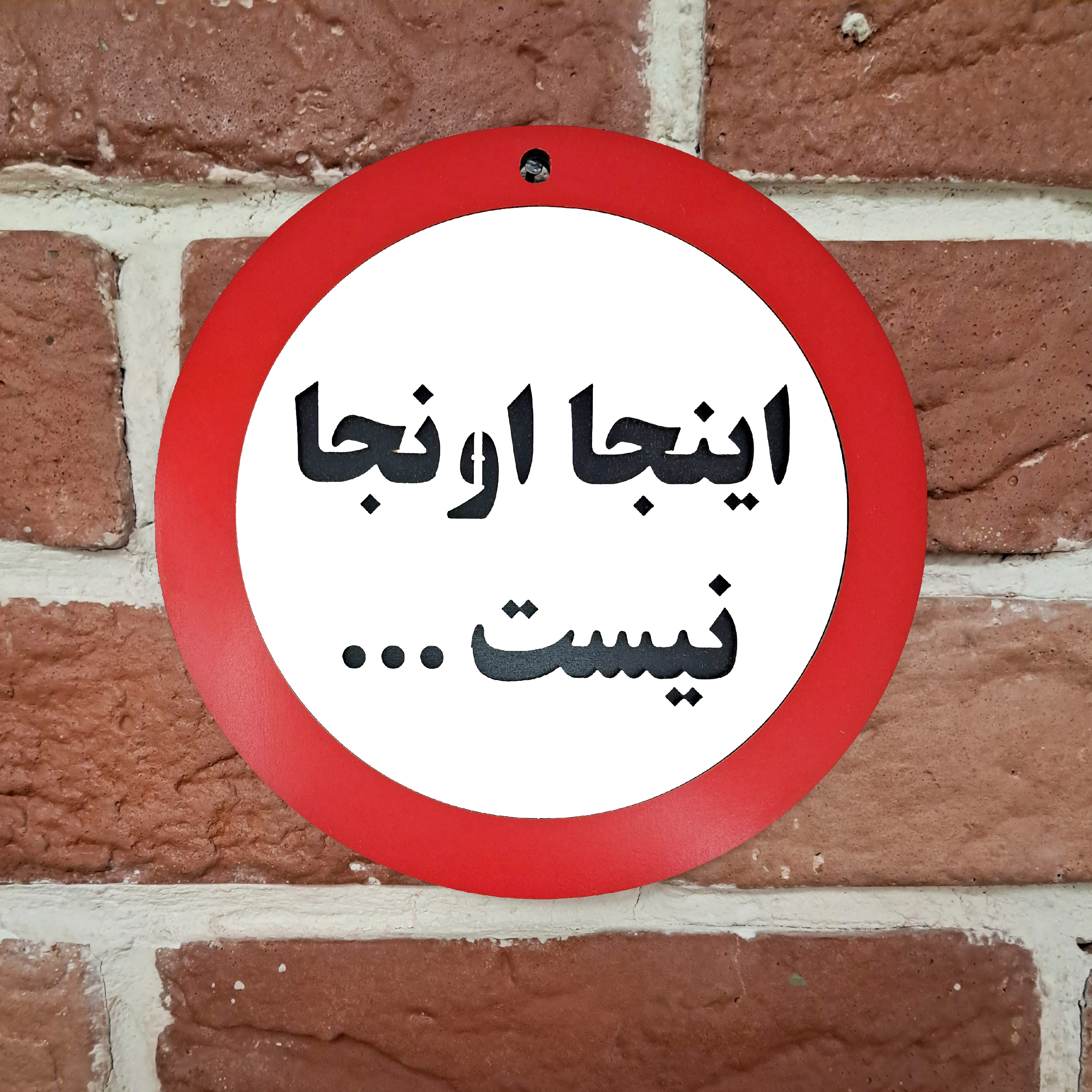 تابلو طنز اینجا اونجا نیست نصب شده روی دیوار