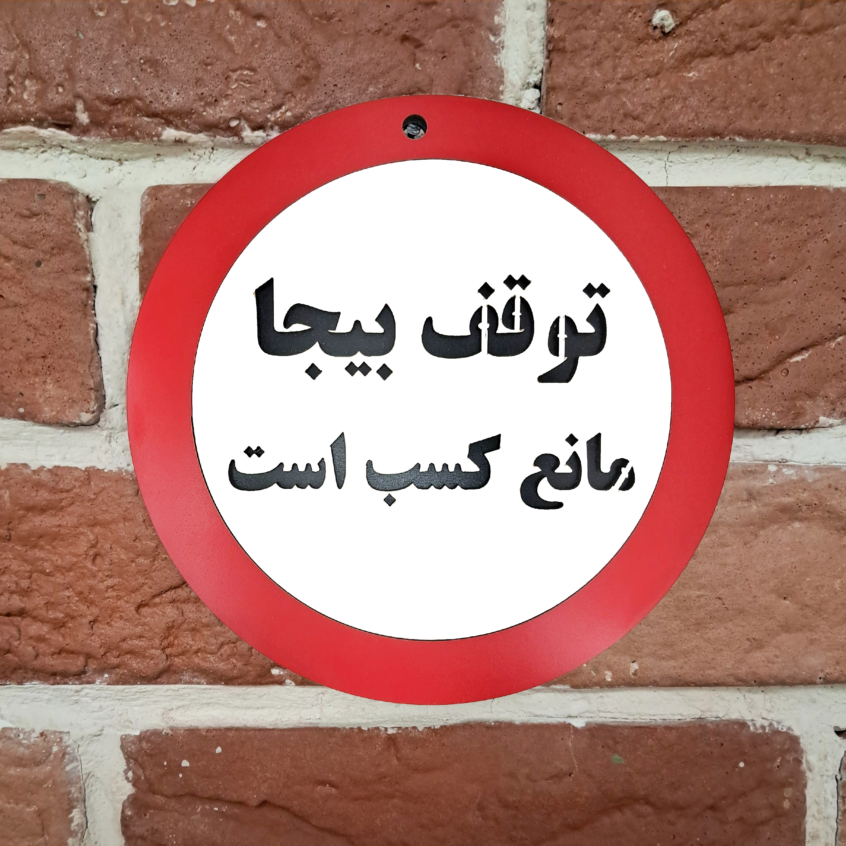تابلو توقف بیجا مانع کسب است، نصب شده روی دیوار آجری