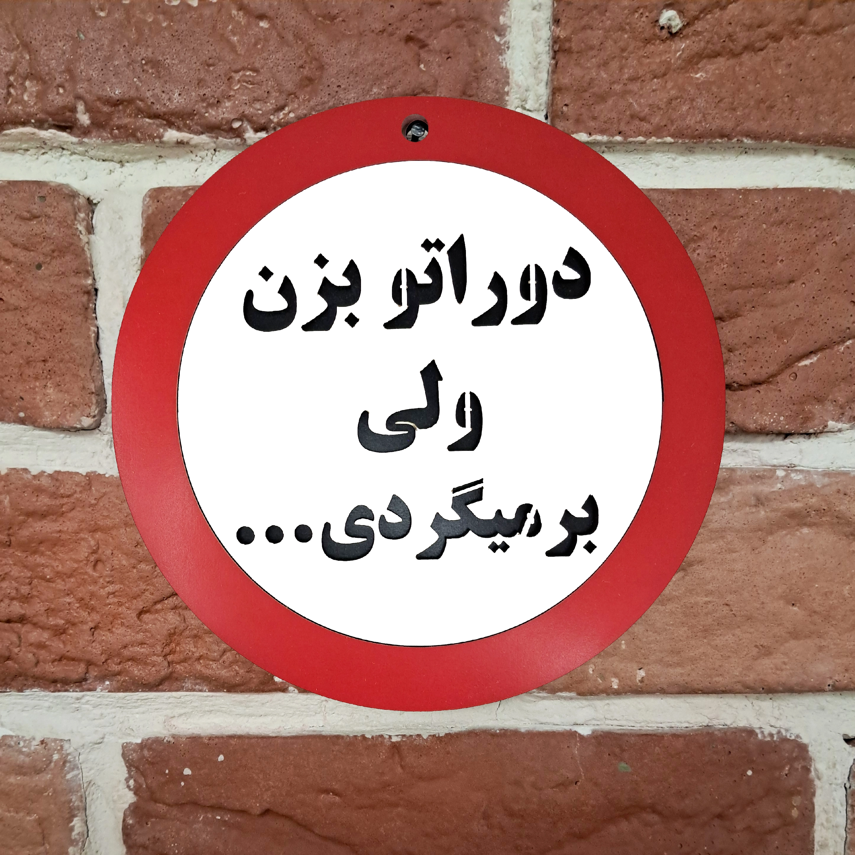 تابلو دیواری متن دوراتو بزن ولی برمیگردی نصب شده روی دیوار با میخ