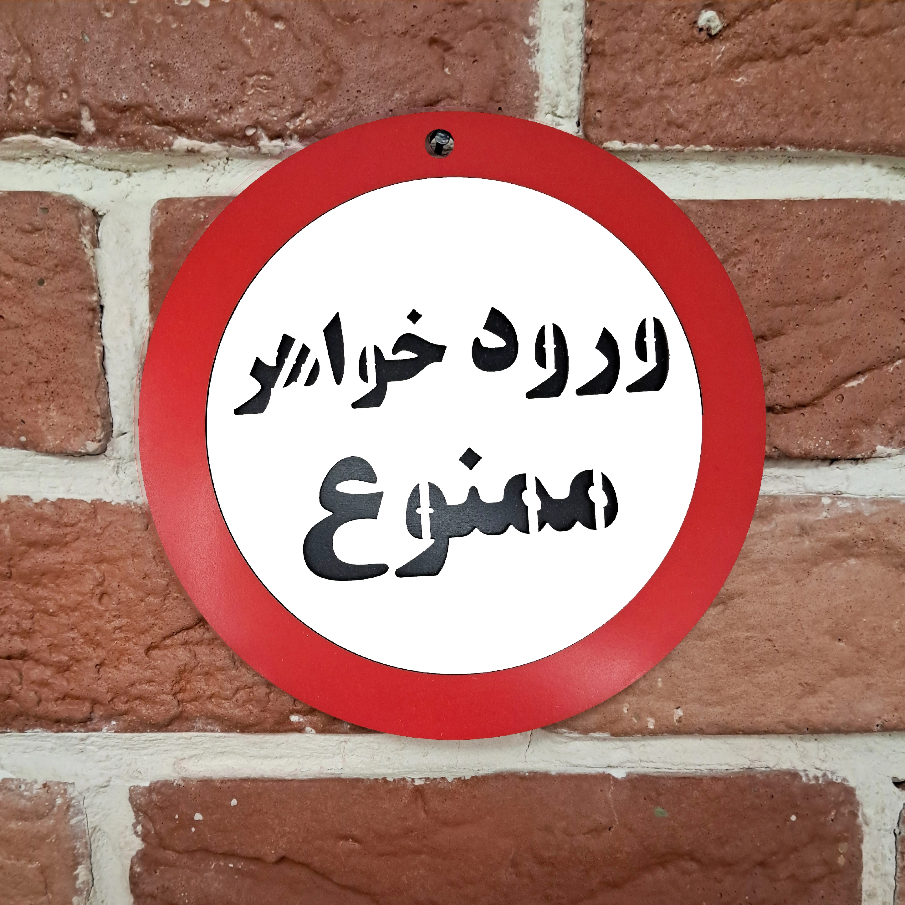 تابلو دیواری و طنز ورود خواهر ممنوع نصب شده روی دیوار آجری با میخ