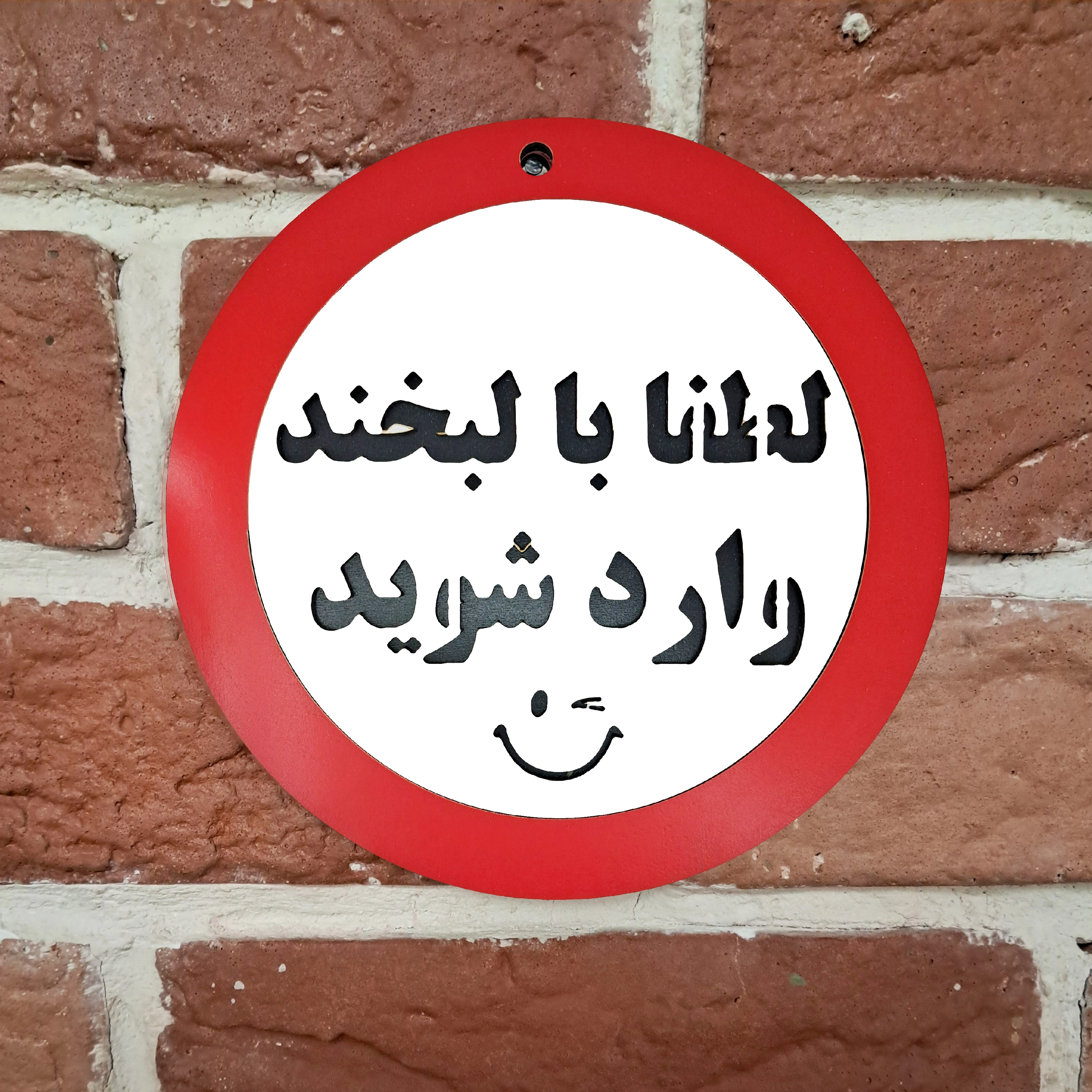تابلو دیواری لطفا با لبخند وارد شوید نصب شده روی دیوار
